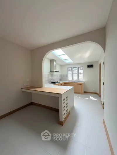 Modern kitchen with open layout and natural light, featuring sleek countertops and a gas stove.