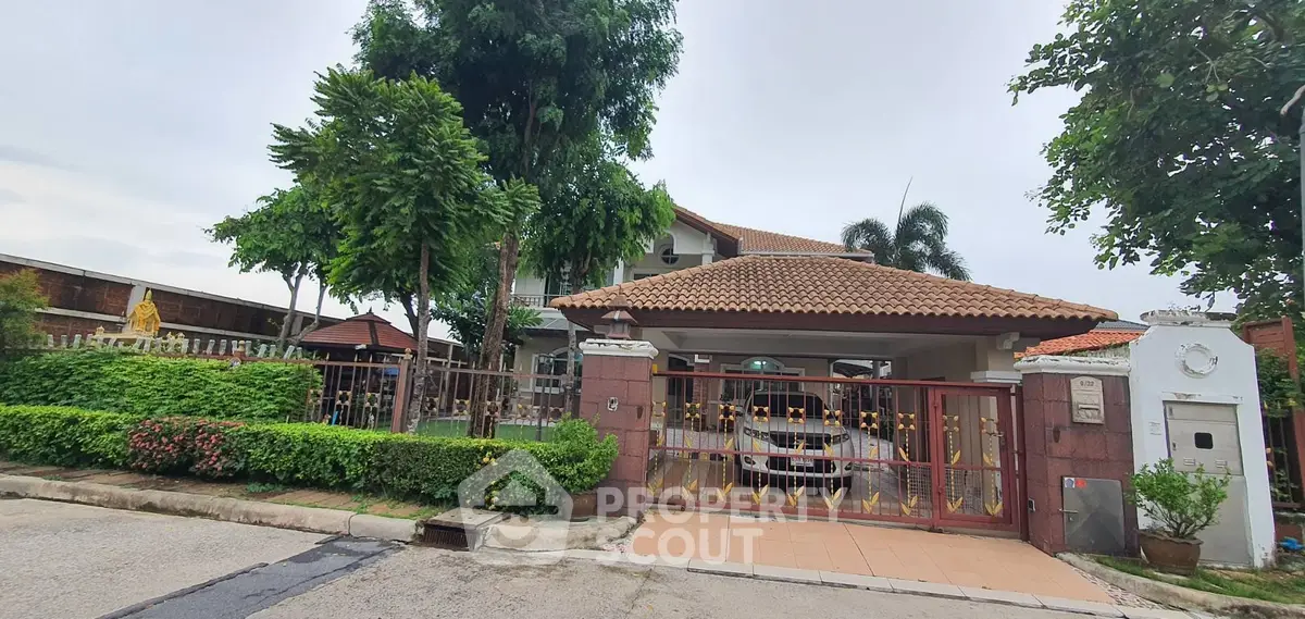 Charming suburban house with lush greenery and secure gated entrance.