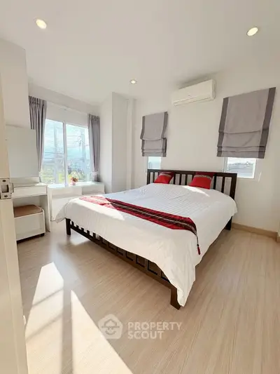 Bright and airy bedroom with modern decor and large window view.