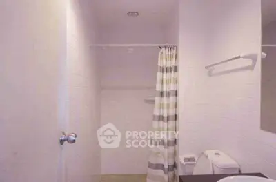 Minimalist bathroom with shower curtain and modern fixtures in a bright, clean design.