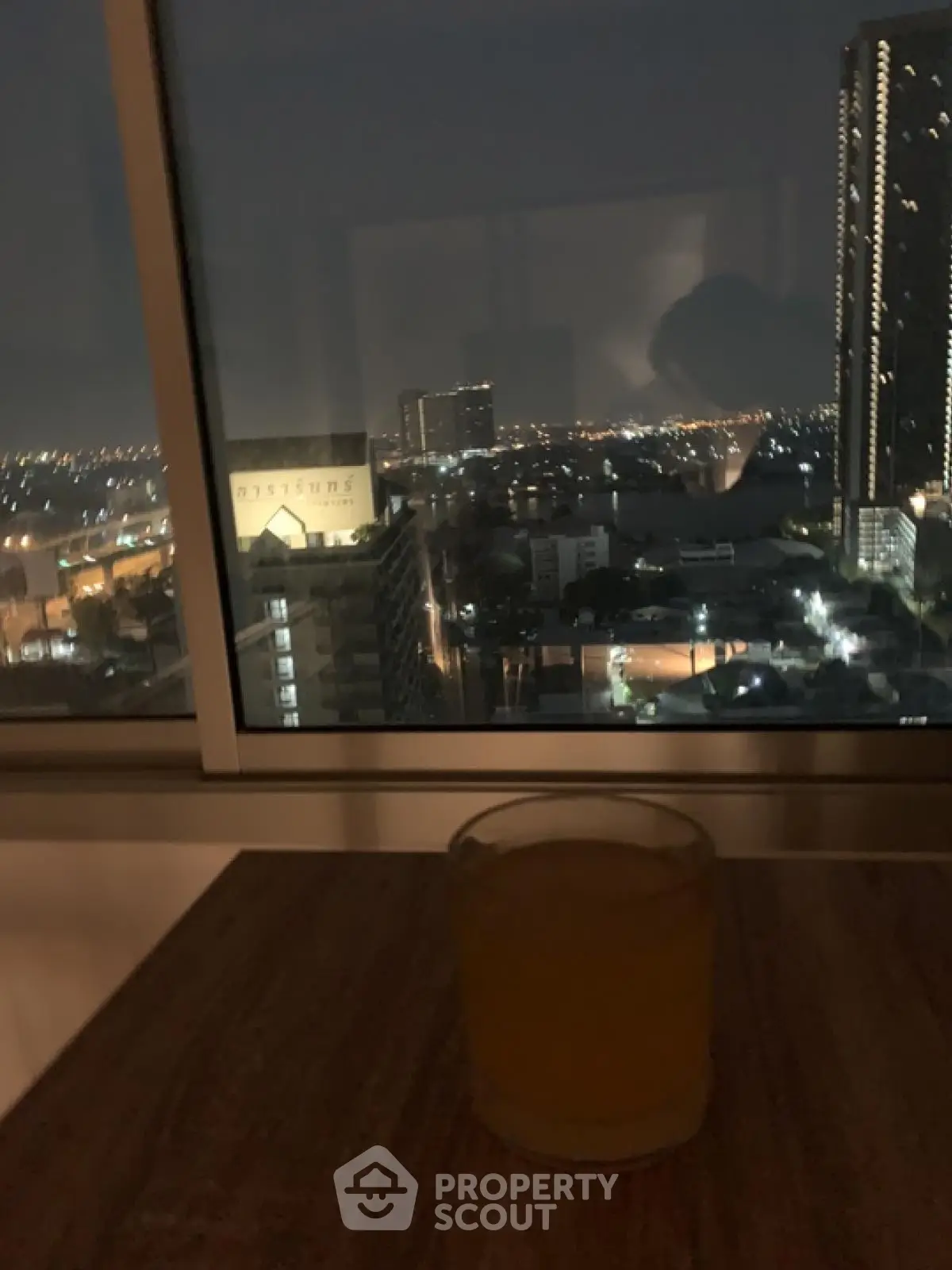 Stunning cityscape view from high-rise apartment window at night with ambient lighting.