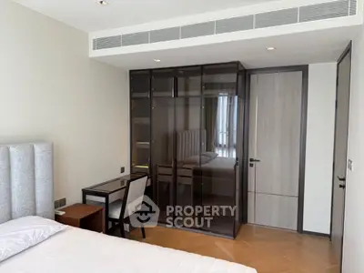 Modern bedroom with sleek glass wardrobe and cozy study area