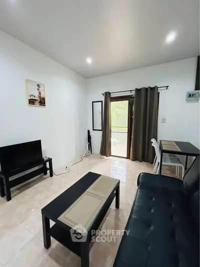 Cozy living room with modern furniture and natural light from balcony.