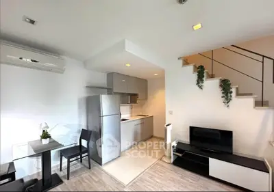 Modern open-plan living room with sleek kitchen and stylish staircase in a contemporary apartment.