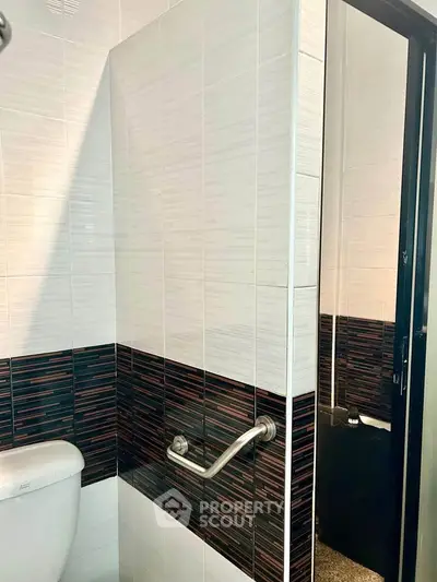 Modern bathroom with stylish tile design and safety handrail.