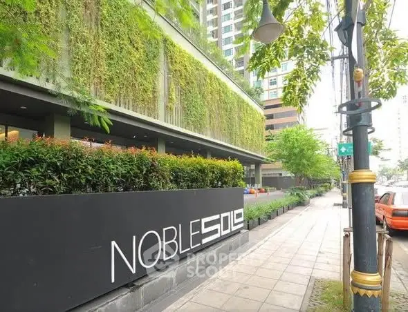 Modern building exterior with lush vertical garden and sleek signage.
