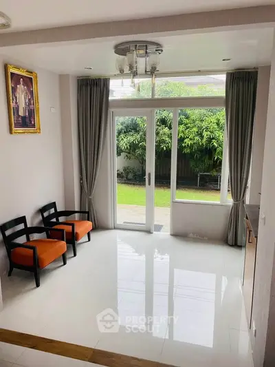 Bright room with garden view and modern decor, featuring elegant chairs and large windows.