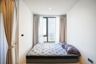 Modern bedroom with large window and elegant curtains in a stylish apartment.