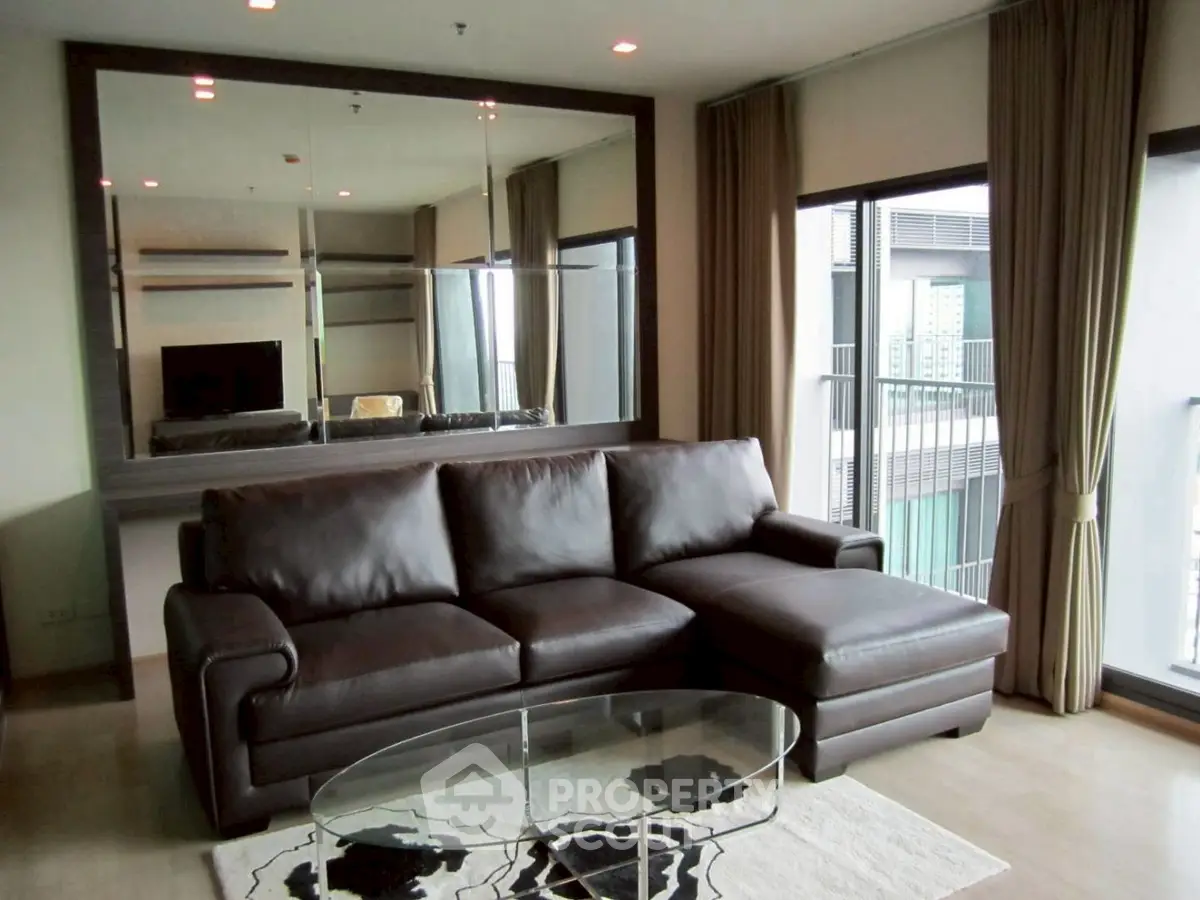 Modern living room with leather sofa and large mirror, featuring a balcony view.