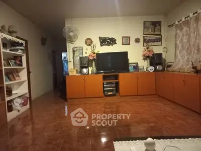 Cozy living room with tiled floor, wooden cabinets, and entertainment center.