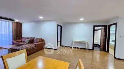 Spacious living room with wooden flooring and modern furniture in a cozy apartment.