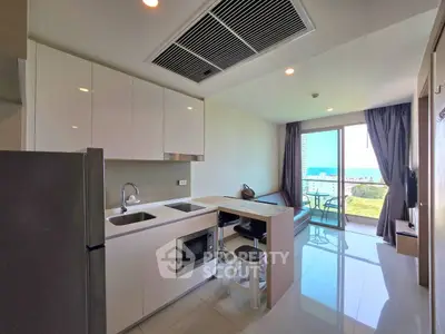 Modern open-layout kitchen and living room with ocean view balcony in luxury apartment.