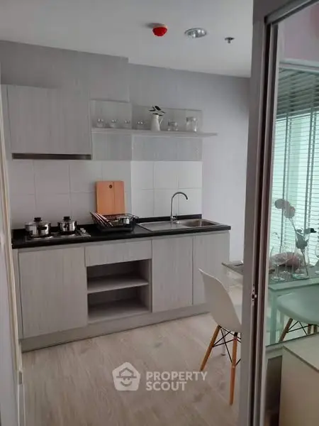 Modern kitchen with sleek cabinetry and dining area in a stylish apartment.