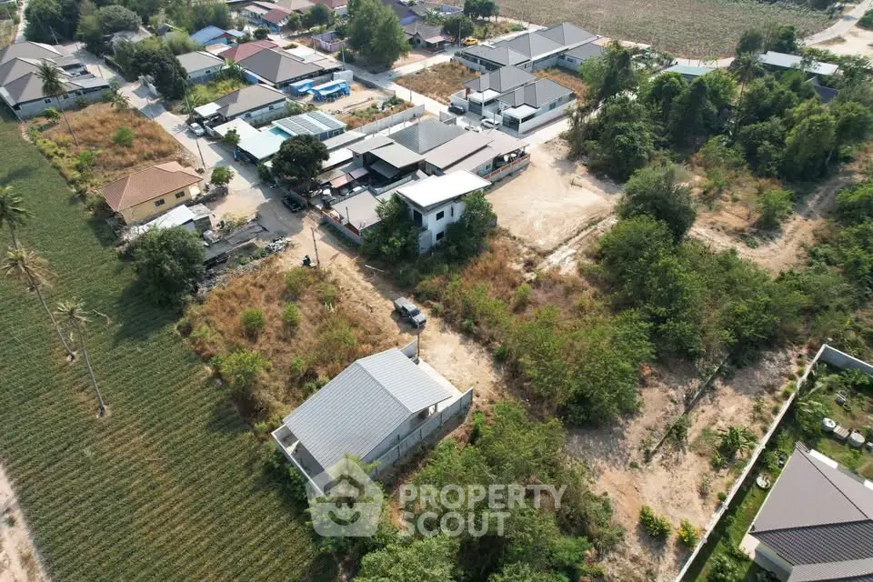 Aerial view of suburban residential area with houses and greenery, showcasing potential real estate development.