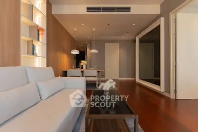 Modern living room with elegant decor and open dining area, featuring stylish lighting and wooden flooring.