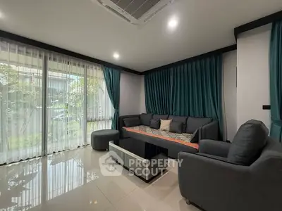 Modern living room with sleek furniture and large windows offering garden view