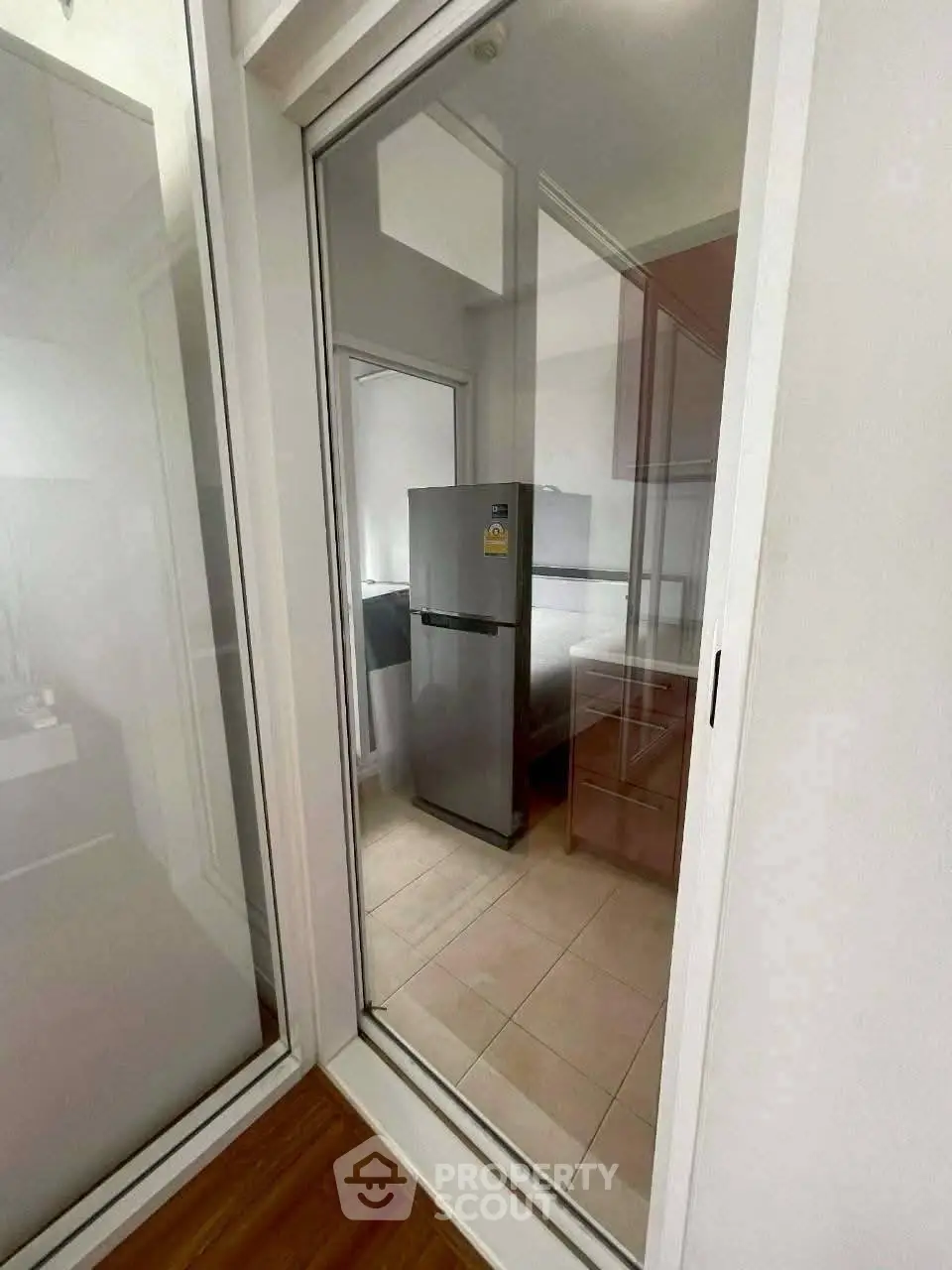 Modern kitchen with sleek refrigerator and glass partition, offering a stylish and functional space.