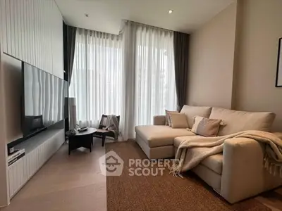 Modern living room with cozy sofa and large TV, featuring elegant decor and natural light.