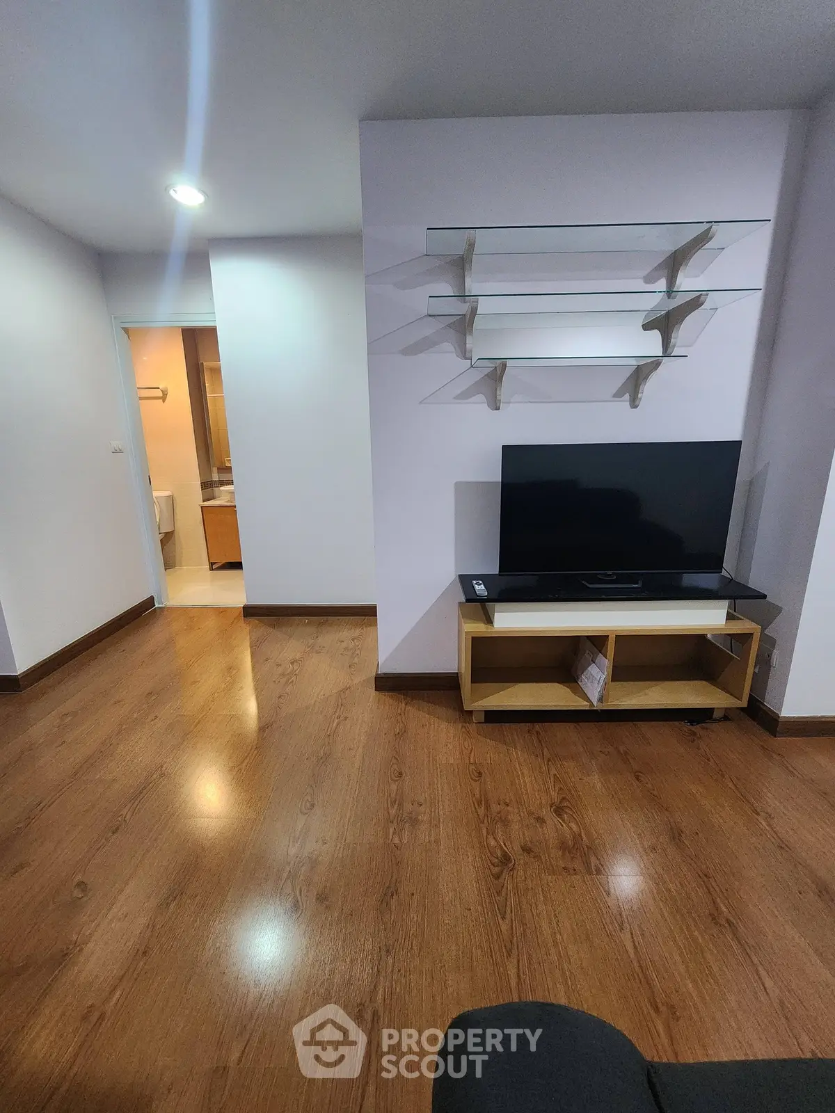 Spacious living room with wooden flooring and modern TV setup, ideal for cozy family gatherings.