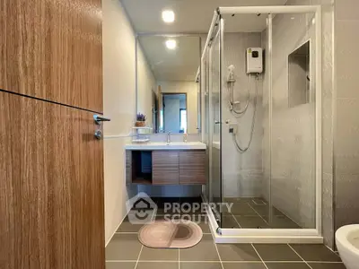 Modern bathroom with glass shower enclosure and stylish wooden vanity.