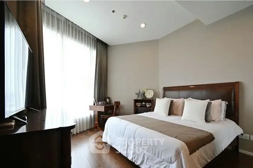 Elegant bedroom with wooden flooring and large window, featuring a cozy bed and stylish decor.