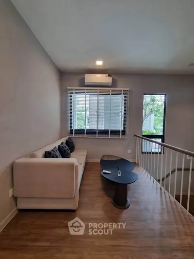 Cozy living room with modern sofa and stylish coffee table, featuring large windows for natural light.