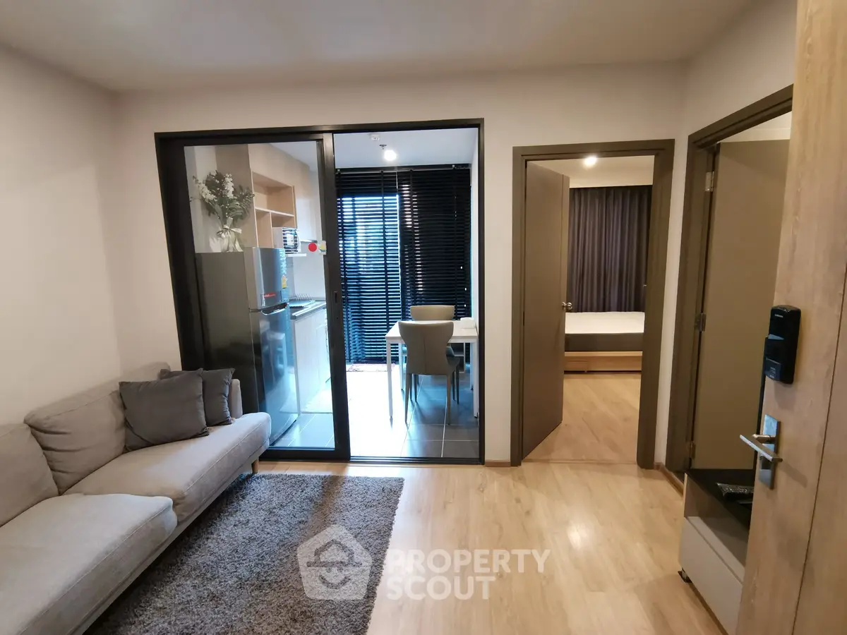 Modern apartment interior with cozy living room and glass-enclosed dining area, featuring stylish decor and natural light.