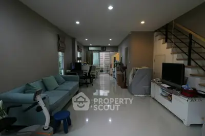 Spacious living room with modern decor and open layout, featuring a cozy sofa and sleek staircase.