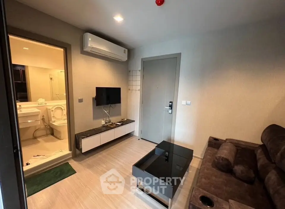 Modern living room with sleek furniture and wall-mounted TV in a cozy apartment.