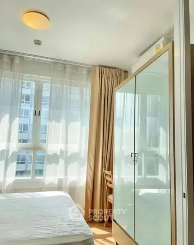 Bright bedroom with large window and modern wardrobe in a high-rise apartment.