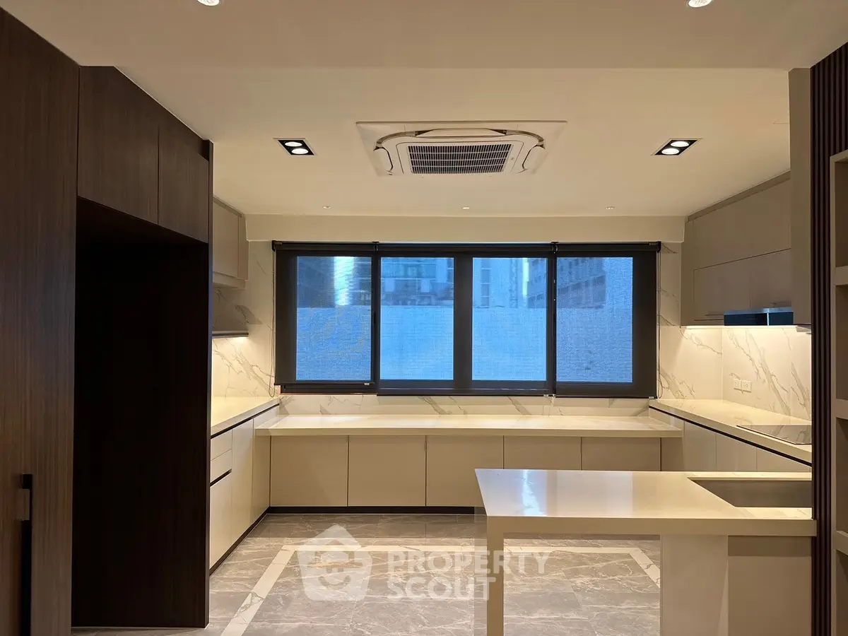 Modern kitchen with sleek cabinetry and large window offering city views.