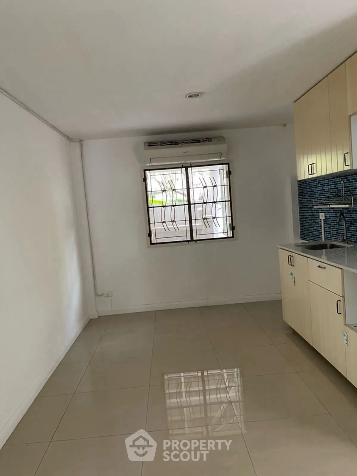 Spacious kitchen area with modern cabinetry and tiled flooring in a bright apartment.