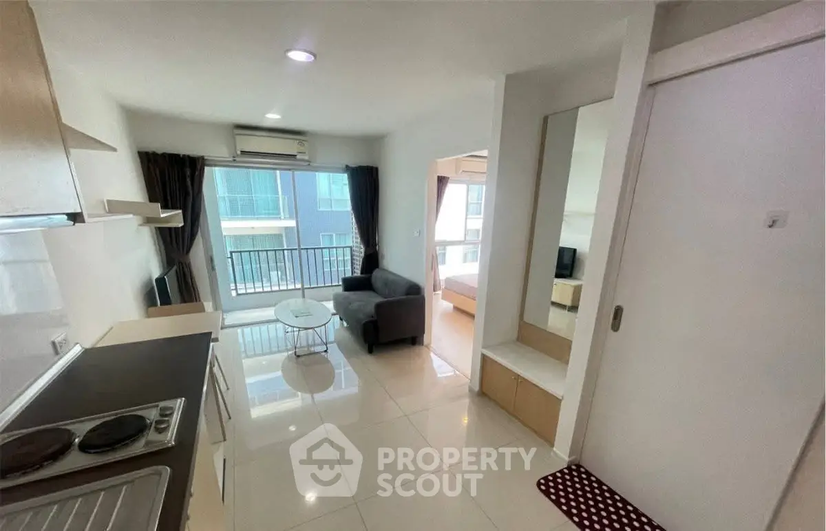 Modern open-layout apartment with kitchen and living area, featuring large windows and balcony access.