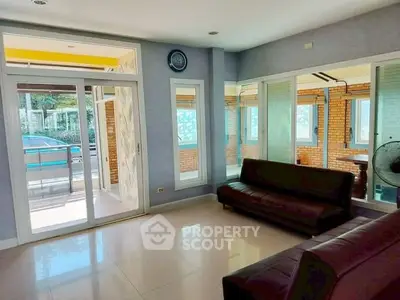 Spacious living room with modern sofas and large windows opening to a sunlit balcony.
