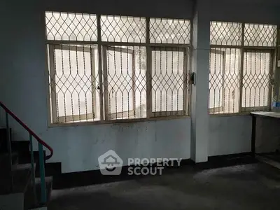 Spacious interior with large windows and security grilles, ideal for renovation.
