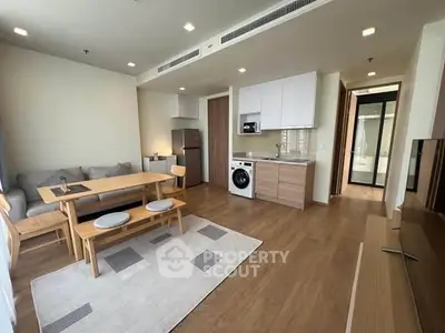 Modern open-plan living room with kitchen, featuring wooden flooring and contemporary furniture.