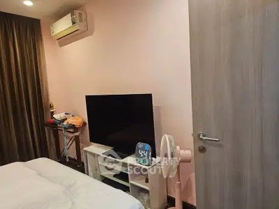 Cozy bedroom with modern TV setup and air conditioning, perfect for relaxation.