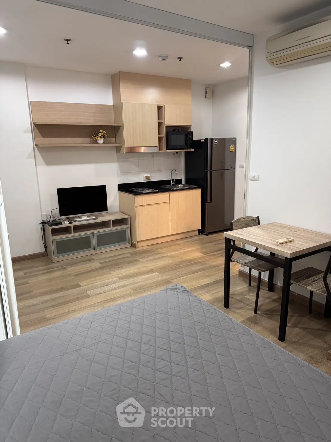 Modern studio apartment with compact kitchen and cozy living area, featuring sleek appliances and stylish decor.
