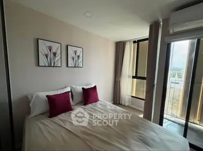 Cozy bedroom with large window and stylish decor, offering natural light and city view.