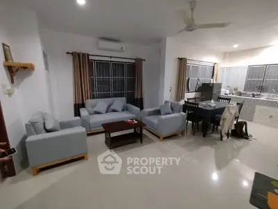 Spacious open-plan living room with modern furniture and kitchen area, perfect for family gatherings.