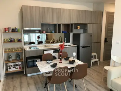 Modern kitchen with sleek cabinetry, marble dining table, and stainless steel appliances in stylish apartment.
