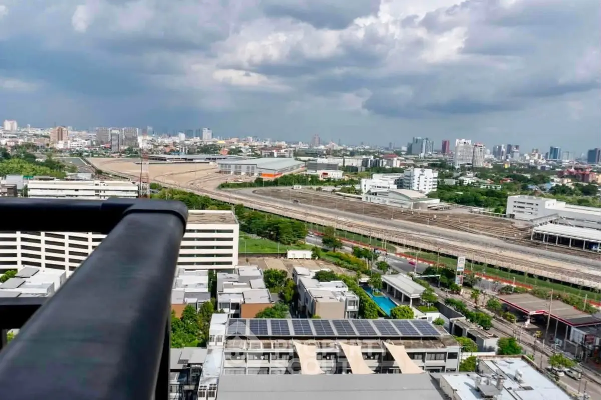 Stunning cityscape view from high-rise balcony overlooking urban skyline and railway tracks.