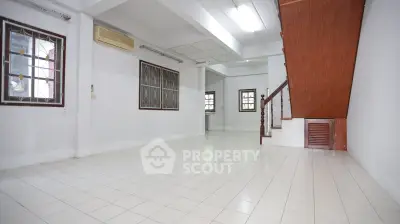 Spacious tiled living room with staircase and natural light