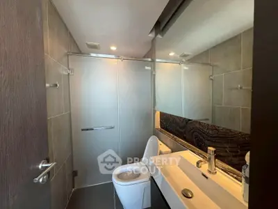 Modern bathroom with sleek fixtures and large mirror in contemporary apartment.