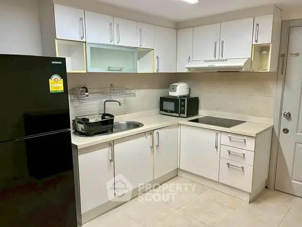Modern kitchen with sleek white cabinets and appliances, featuring a compact layout and contemporary design.