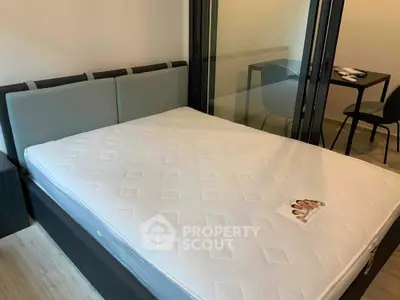 Modern bedroom with sleek glass partition and cozy bed setup.
