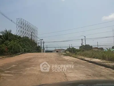 Spacious plot of land with clear sky and surrounding greenery, ideal for development.