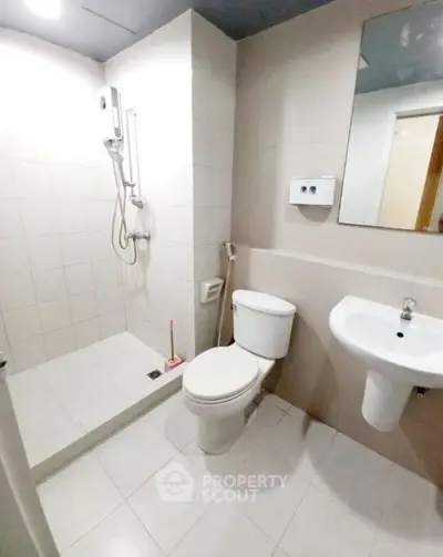 Modern bathroom with shower, toilet, and sink in a sleek tiled design.