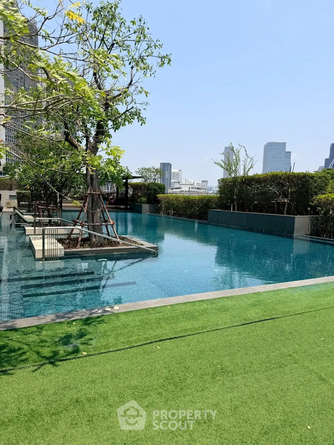 Luxurious rooftop pool with stunning city views and lush greenery, perfect for relaxation and leisure.