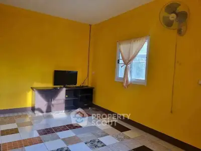 Vibrant yellow room with unique tiled flooring and wall-mounted fan, perfect for creative living space.